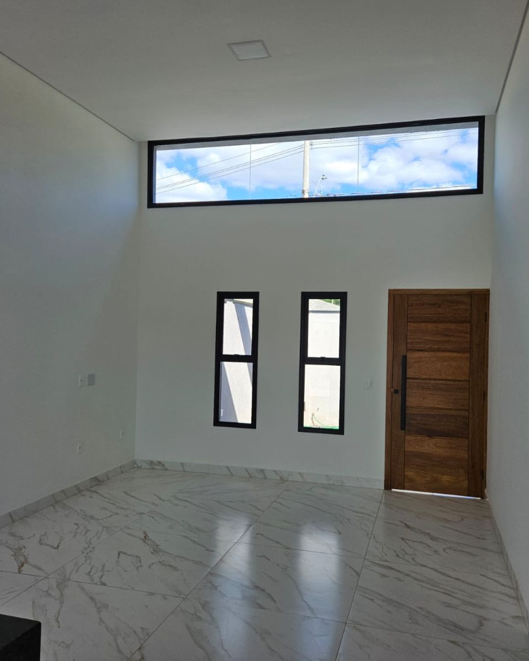 Sala com pé-direito duplo, janelas altas e porta de madeira — Bela Aliança, Campinas